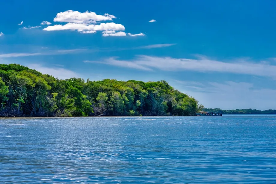 Blue lagoon edged with green trees under a sky of white clouds